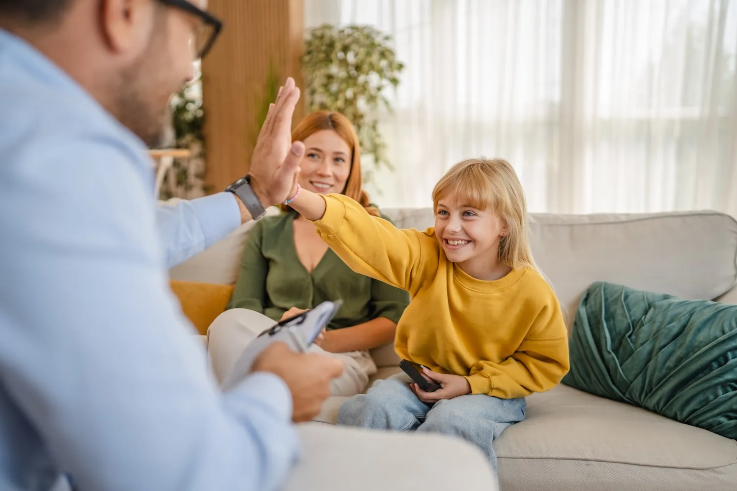 Kind gibt einem Berater ein High-Five, die Mutter freut sich mit